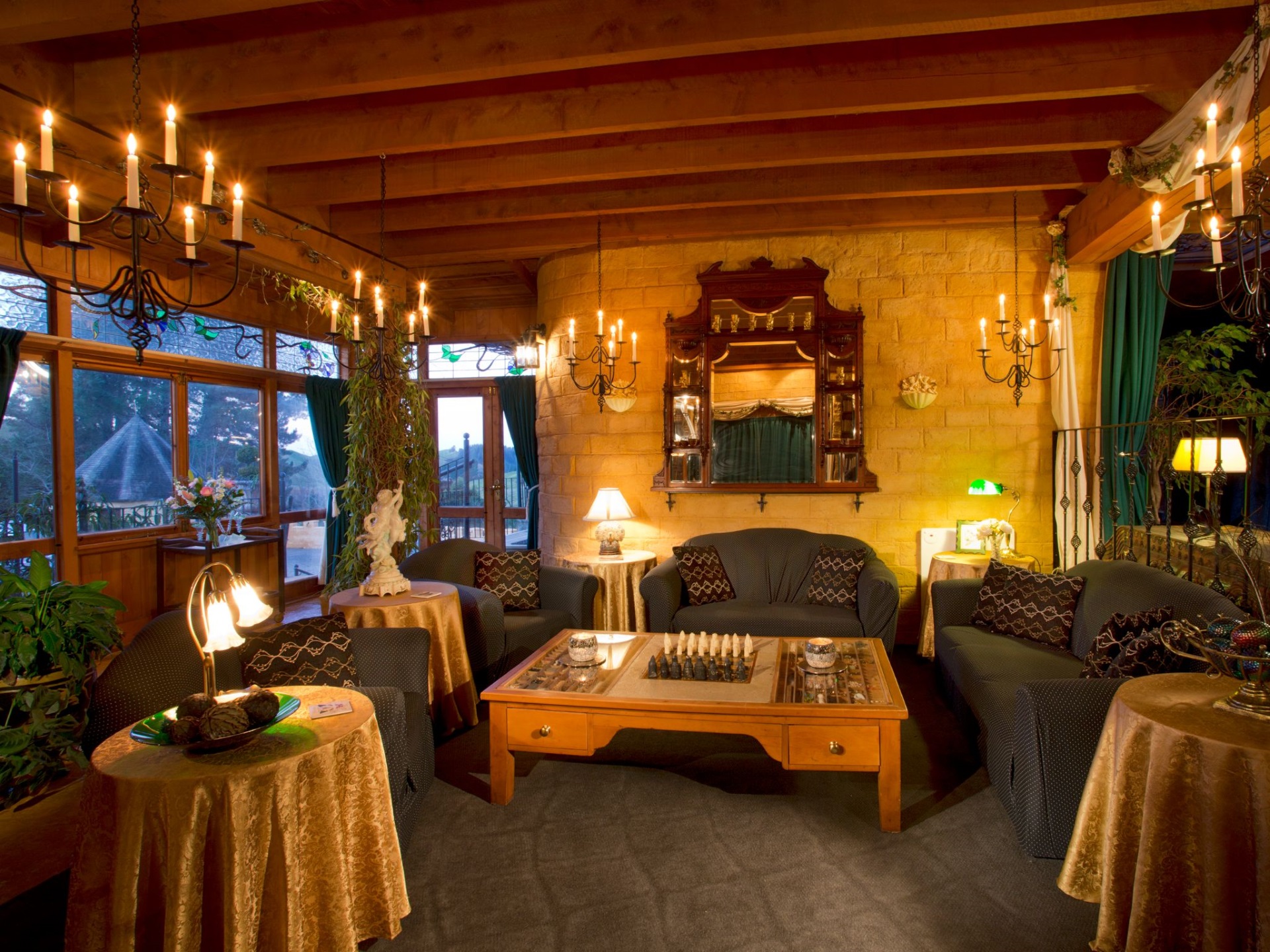 Candlelit lounge with stone walls, timber beams, candleholders and antique furnishings