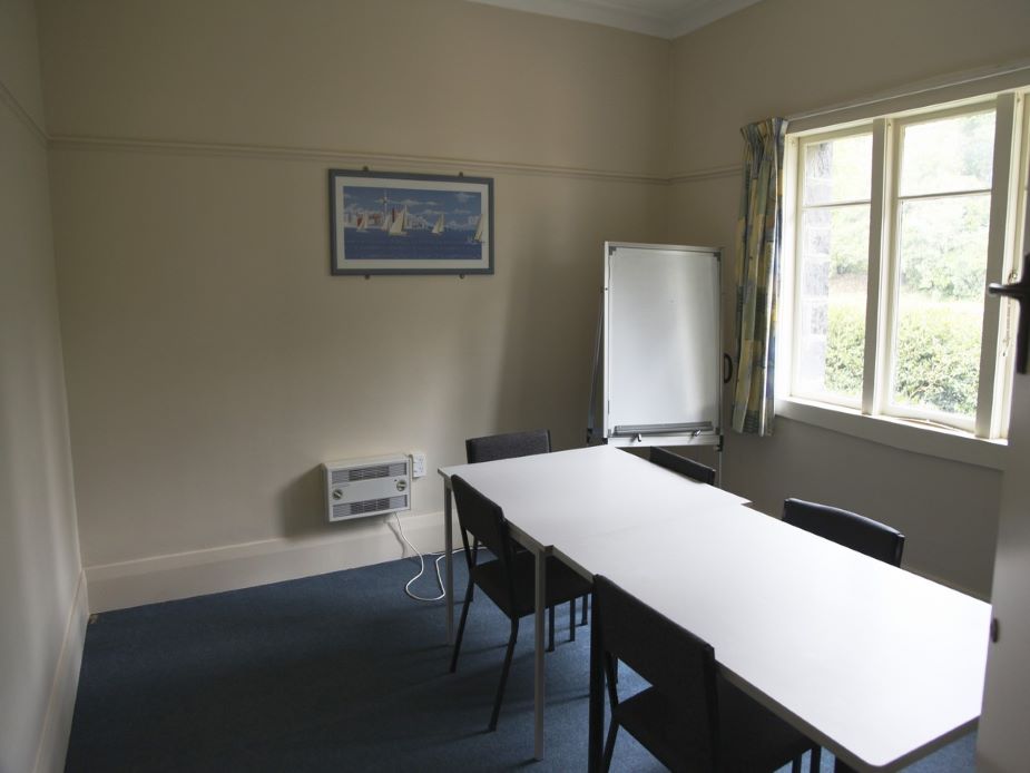 Small meeting room with table, chairs, whiteboard and framed artwork on wall