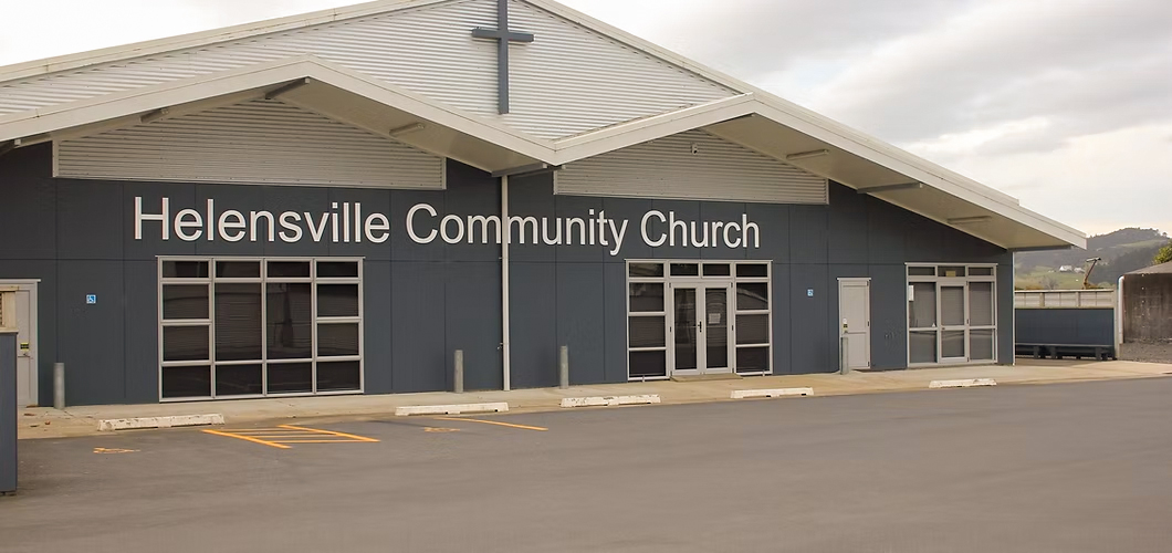 White timber church with pointed gothic window and red roof, driveway entry with signage