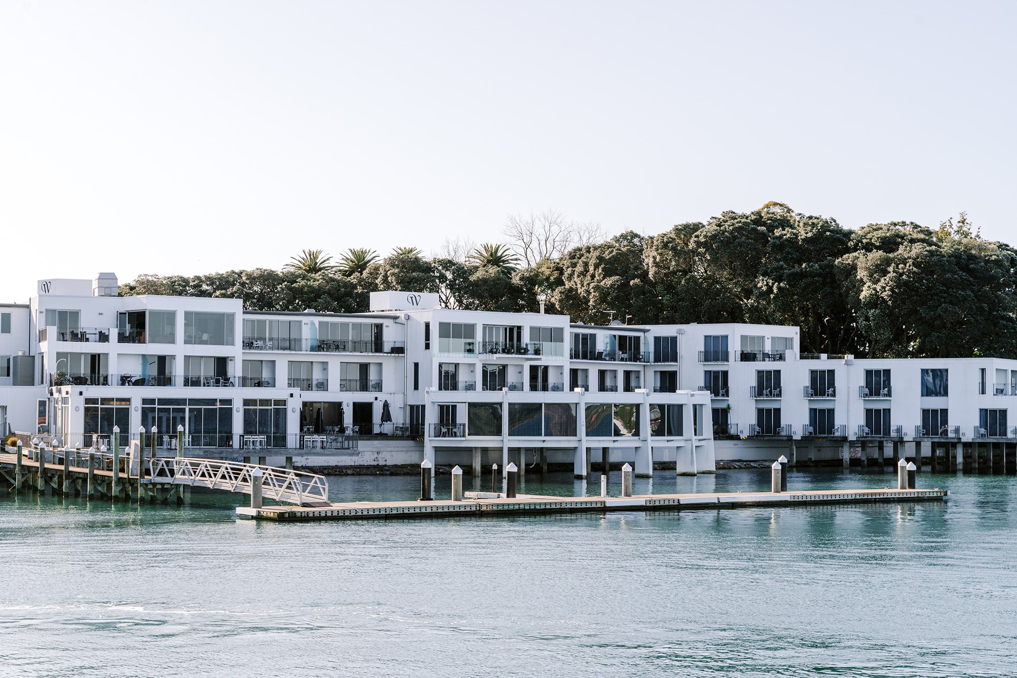 White render building corner over water at golden sunset with bridge in background