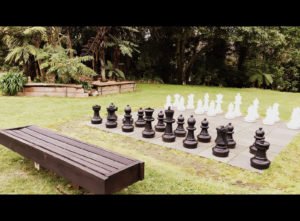 Oversized chess set on a lawn area surrounded by trees