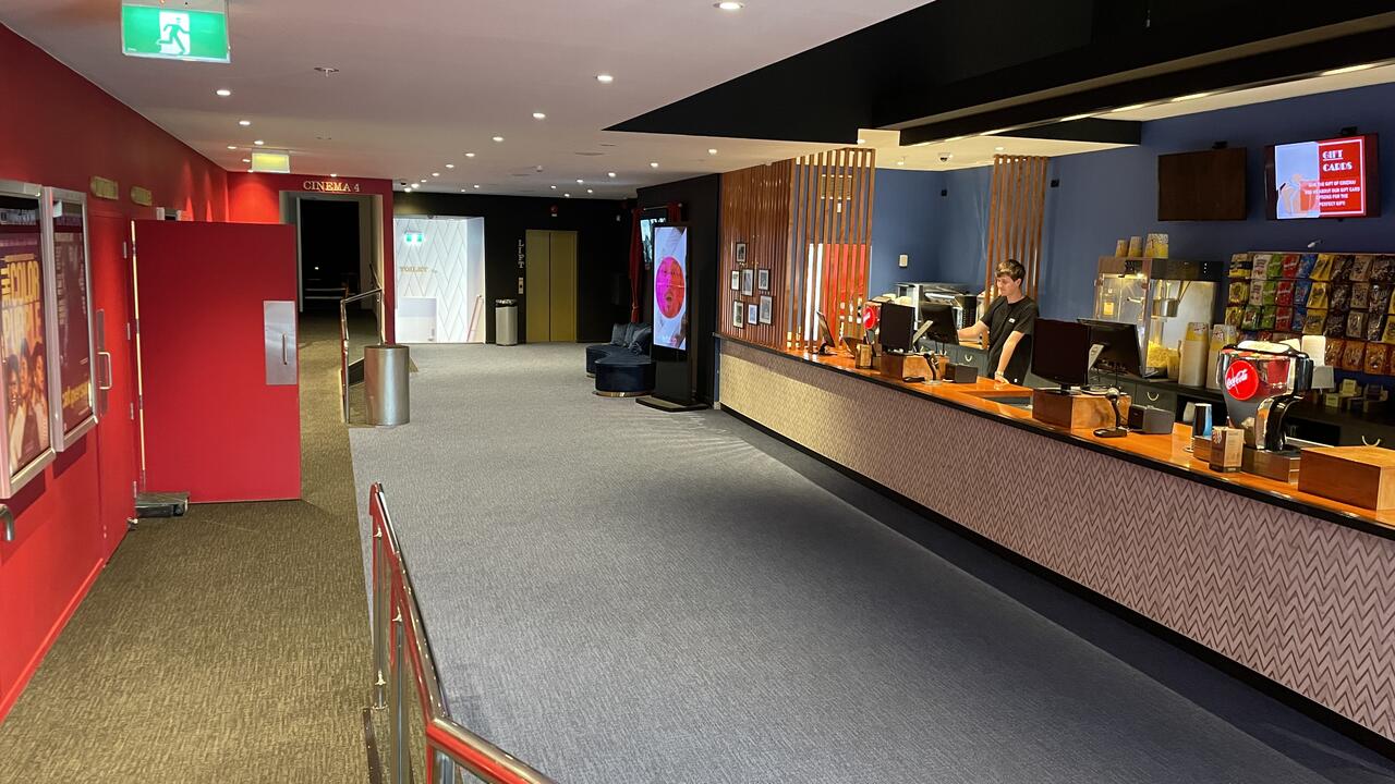 Cinema foyer with ticket counter, red walls, and carpet