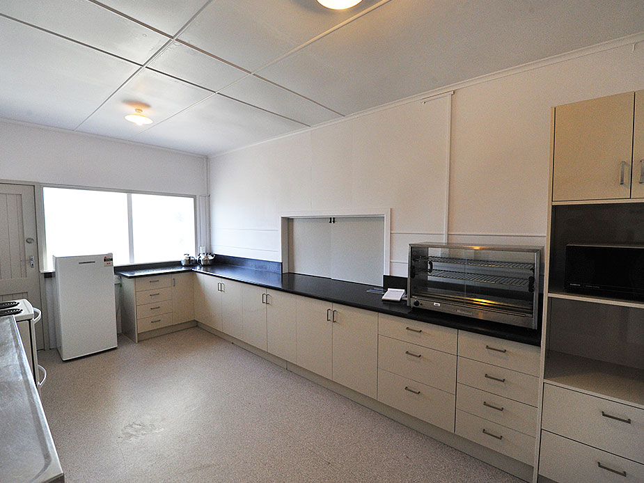 Hall kitchen with white cabinetry, dark benchtops and commercial appliances