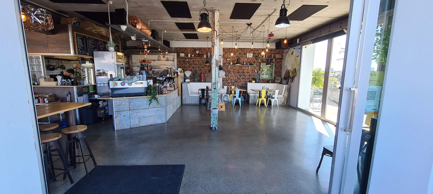 Cafe interior with exposed brick wall, concrete floor, and pendant lights
