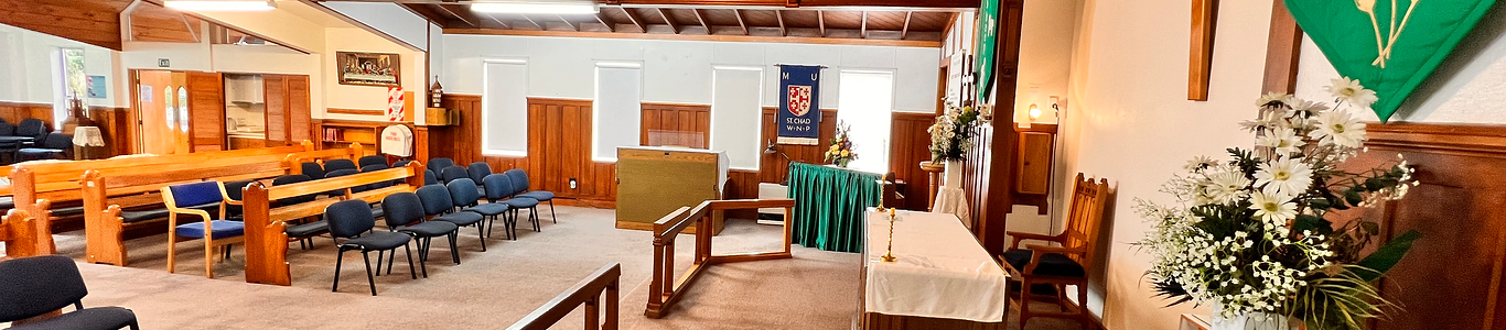 Timber-pewed chapel interior with an altar table, flags, and timber panelling on the walls