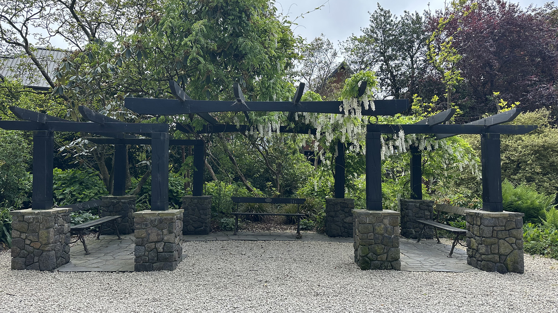 Pergola with stone pillars and hanging flowers in a garden reserve