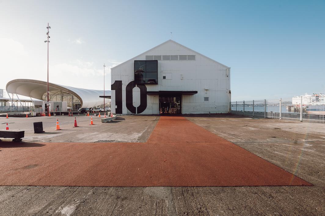 Large white gabled shed building with bold number 10 on facade, waterfront setting