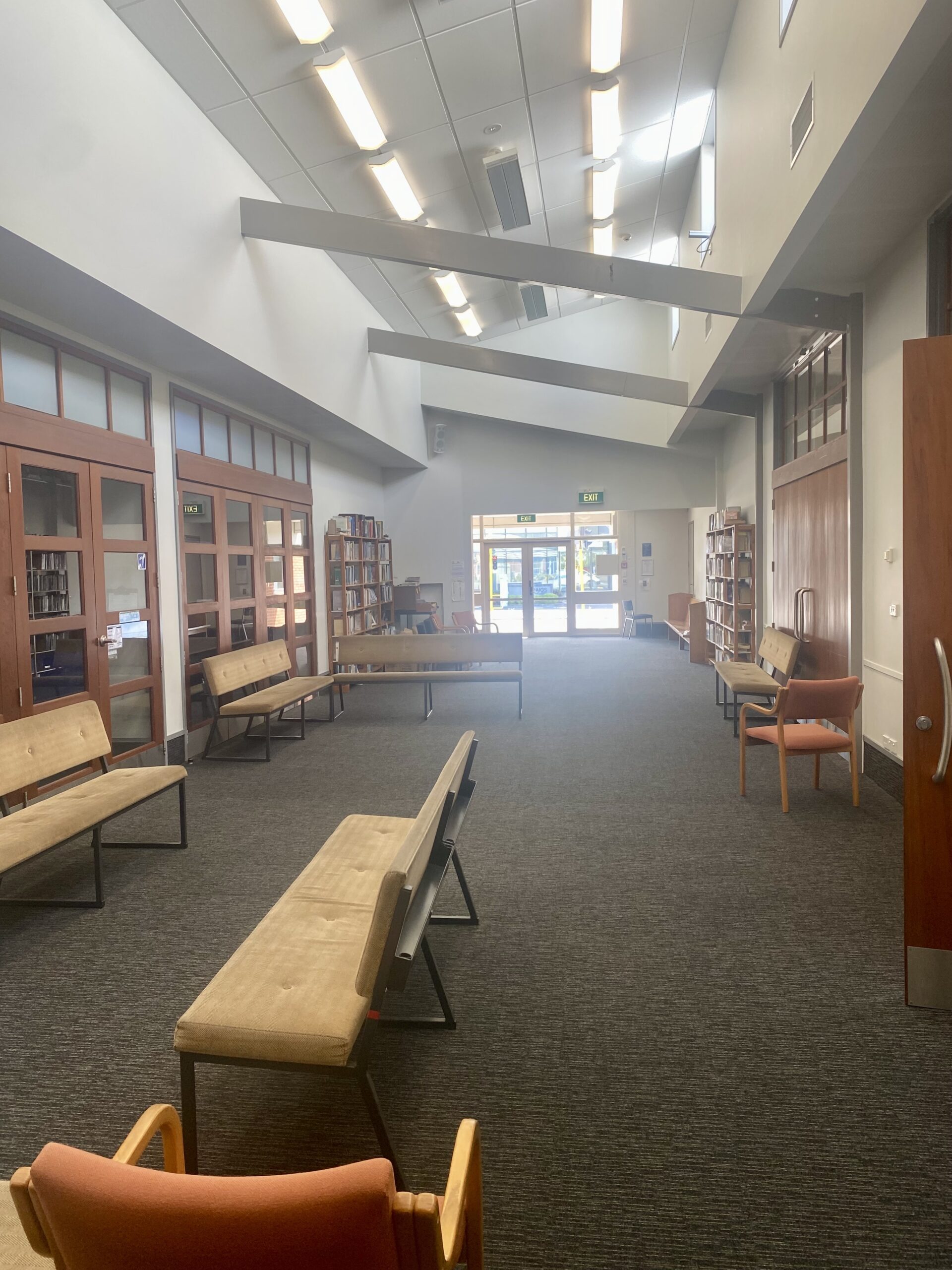 Corridor with timber-panelled walls, bookshelves, and bench seating