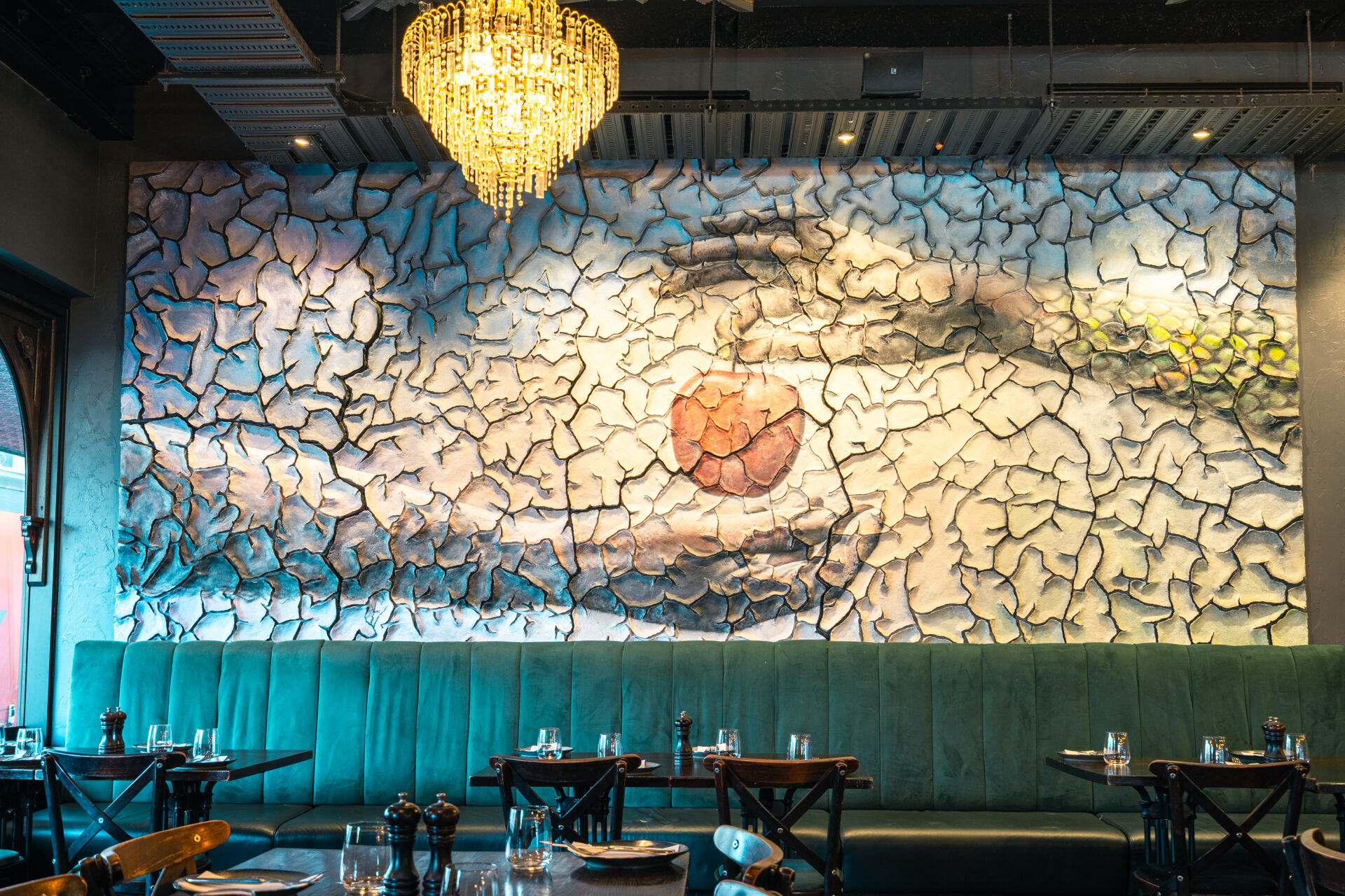 Close-up of decorative stone feature wall with chandelier above velvet banquette seating