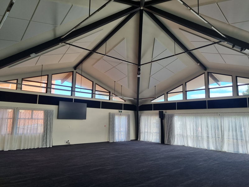 Large octagonal hall with high vaulted ceiling, exposed beams and sheer curtains