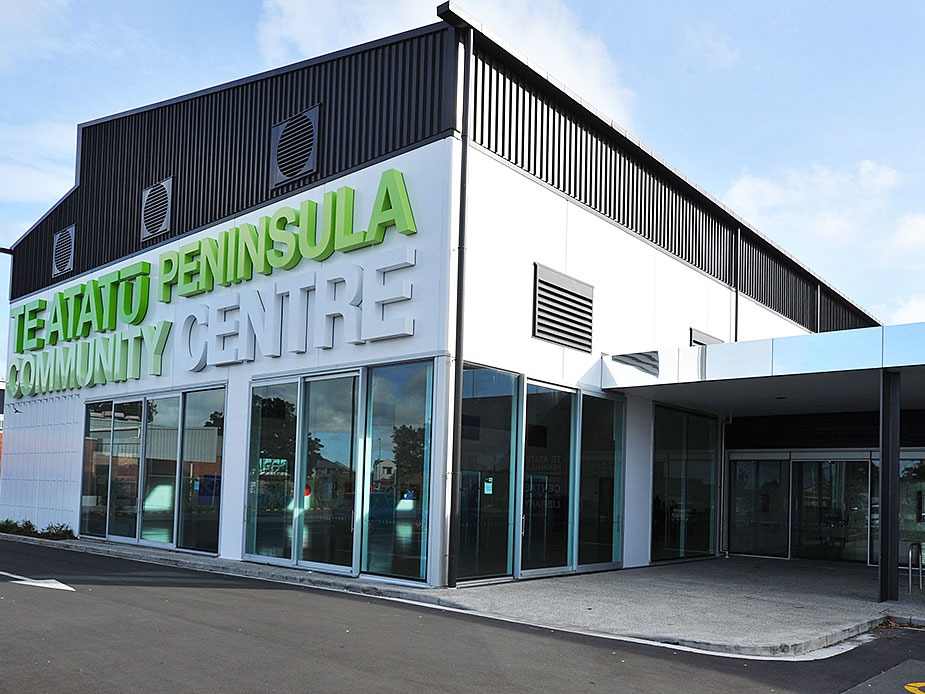 White and dark two-storey building with green signage and large glazed ground-floor shopfront