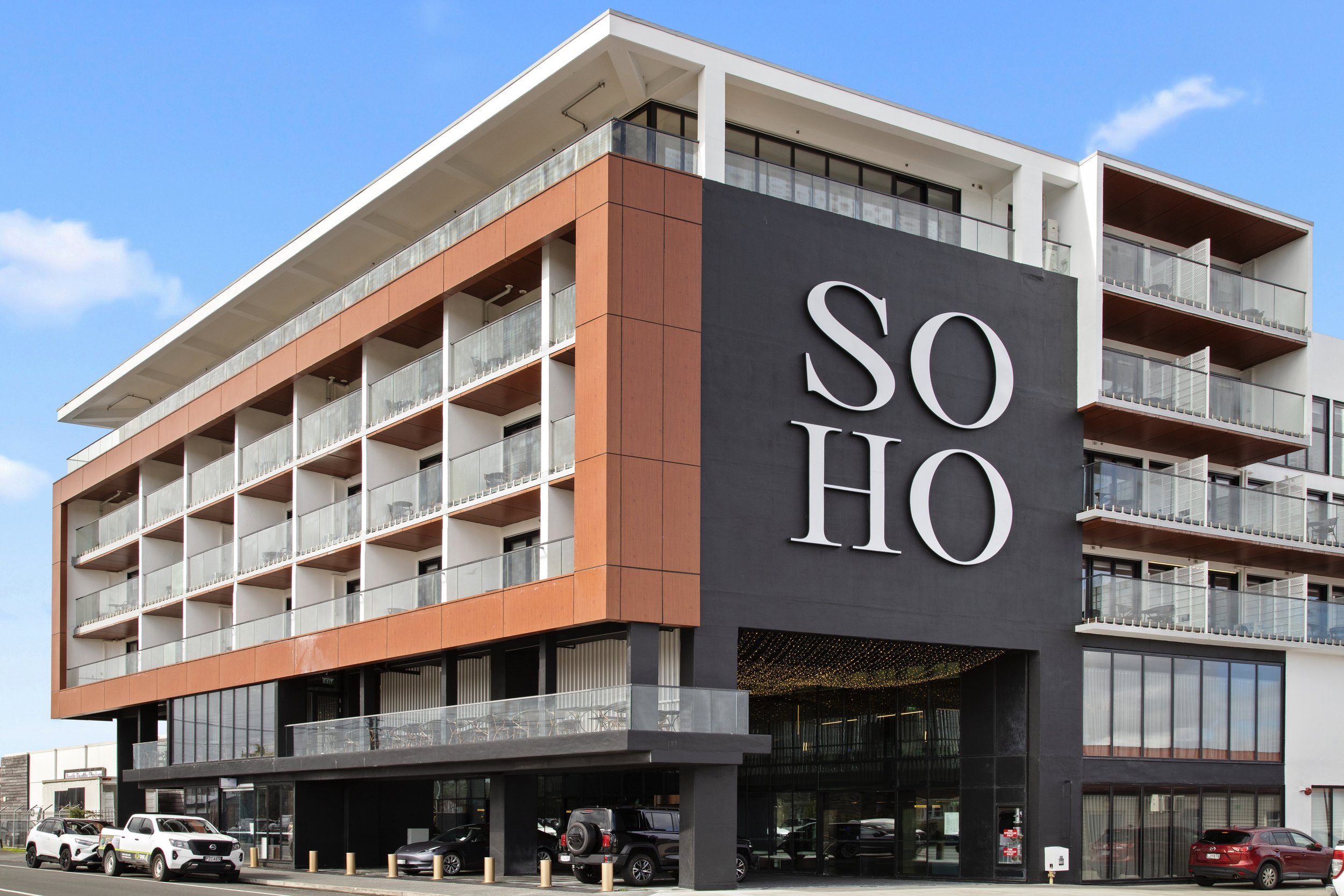 Multi-storey building exterior with terracotta cladding, balconies, and large branded signage, street level