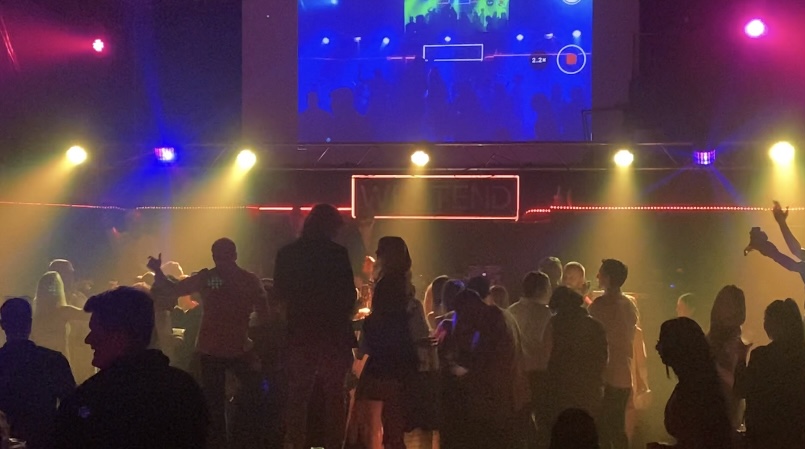 Dark nightclub interior with coloured stage lights and crowd on the dance floor
