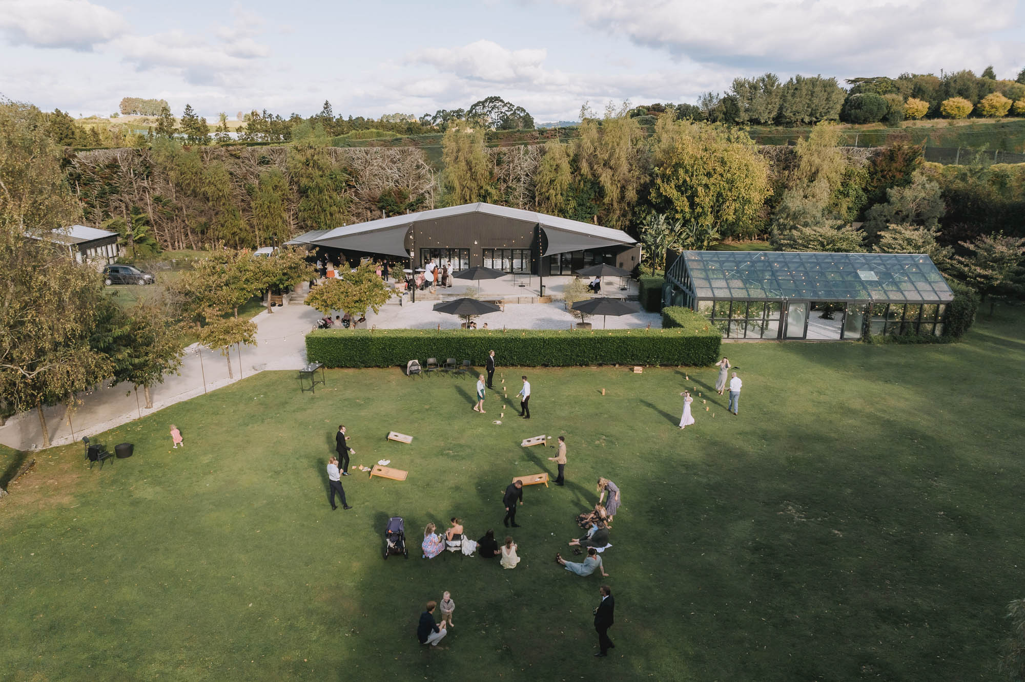 Aerial view of venue pavilion, glass building, and lawn with wedding guests