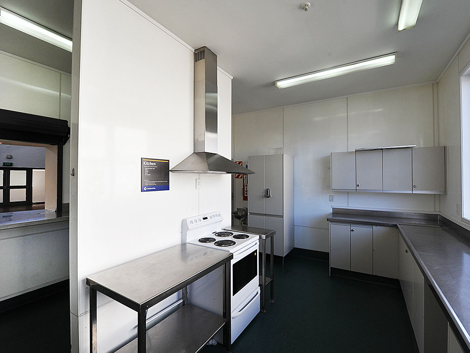 Hall kitchen with commercial range, stainless benchtops and overhead ventilation hood