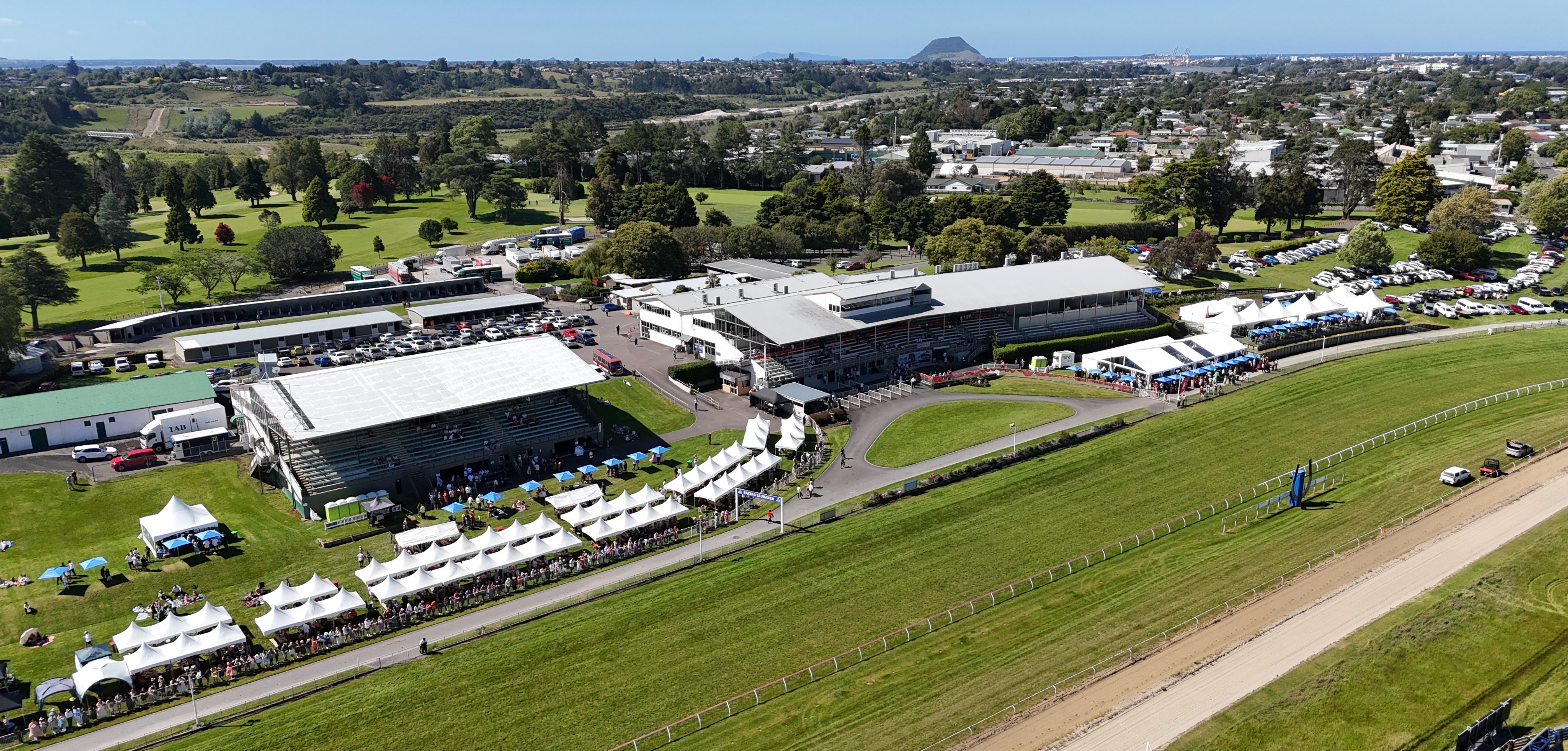 Aerial view of racecourse grandstand and track with marquee tents and crowds