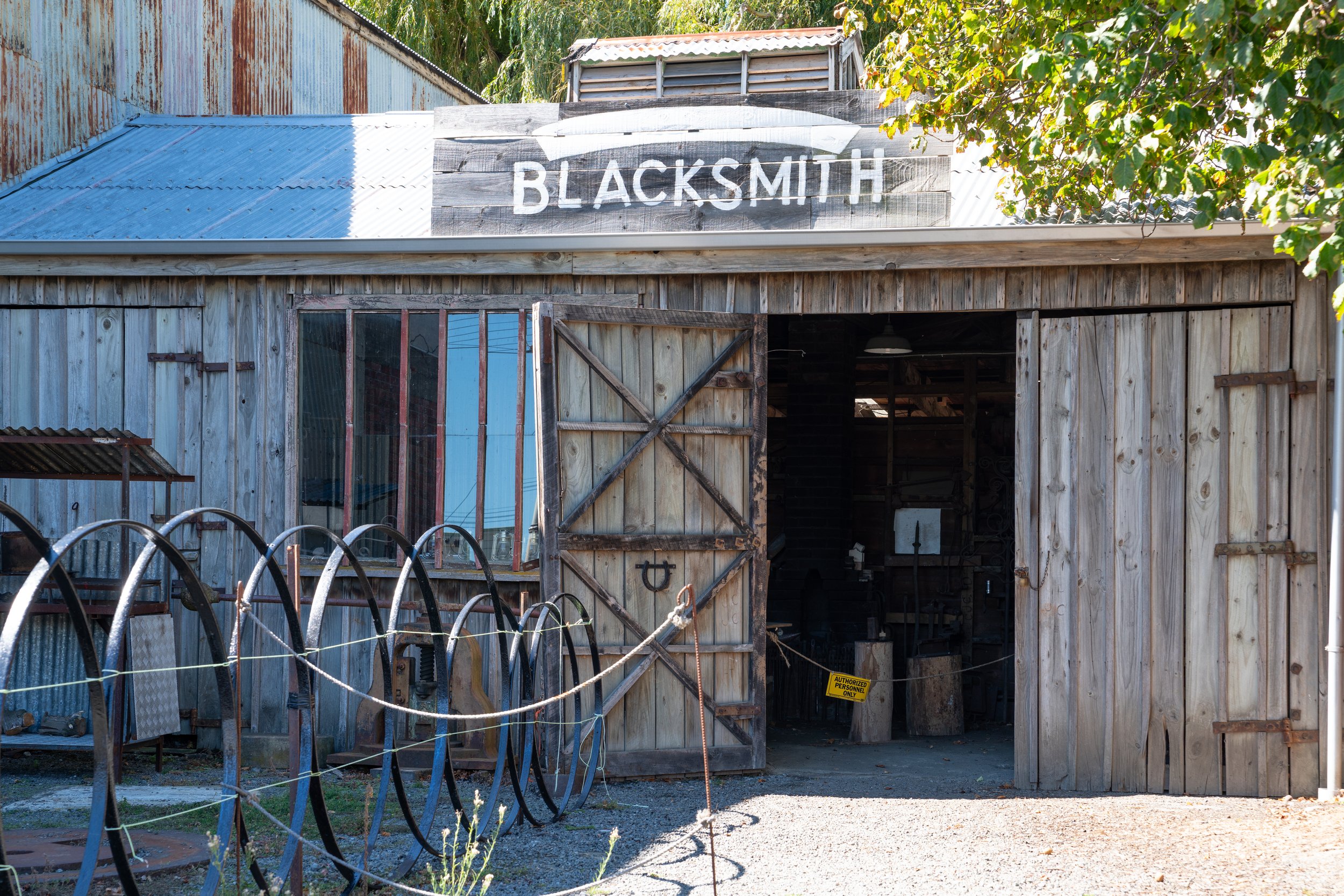 Weatherboard Blacksmith workshop with vintage wheel and open barn doors