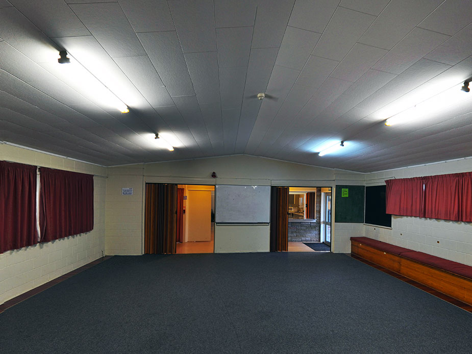 Empty hall with carpet, curtained windows and projection screen at one end
