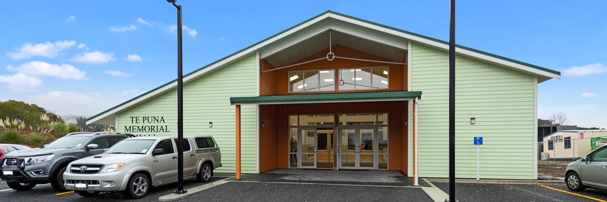 Light green clad hall exterior with signage and carpark