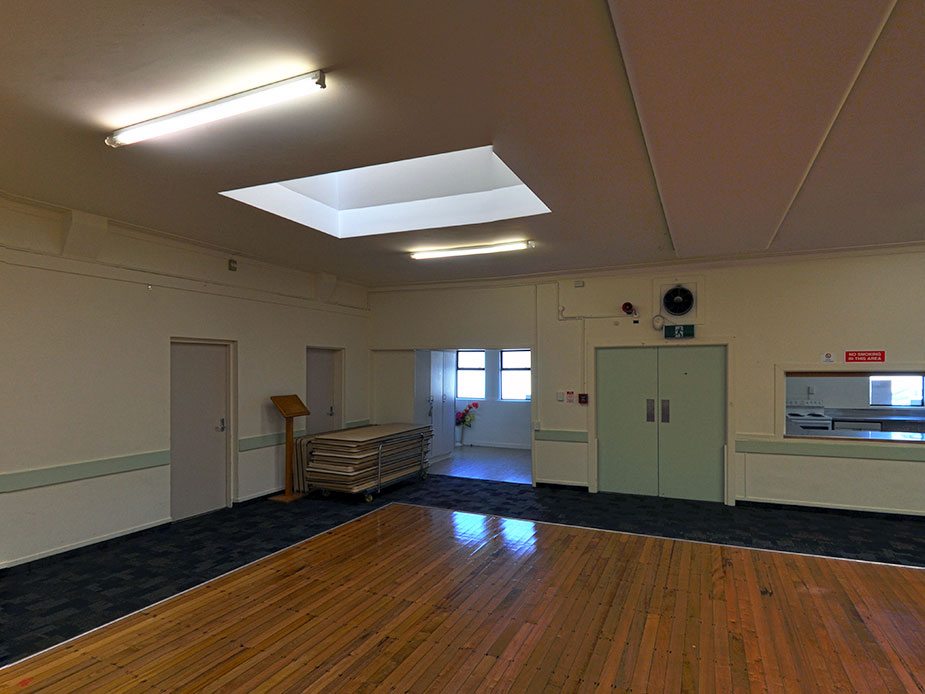 Plain hall with timber and carpet floors, skylight and folded tables