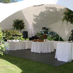 Marquee set with tables and linens on a lawn with floral centrepieces