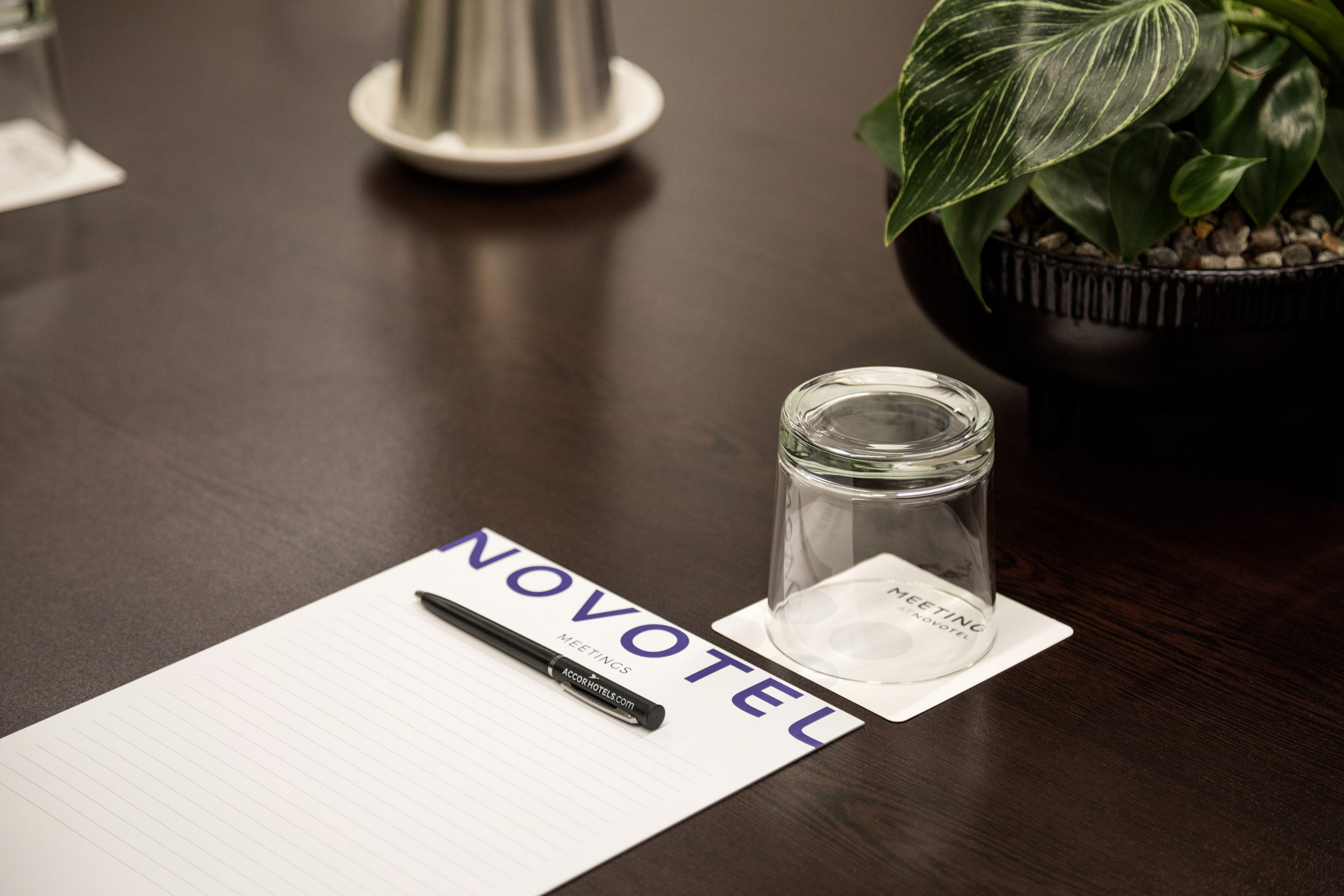 Meeting room with branded notepad, pen and glass on a dark table