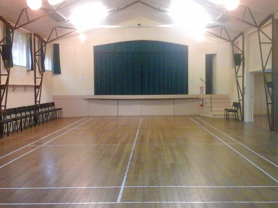 Large hall with timber floor, raised platform and rows of chairs