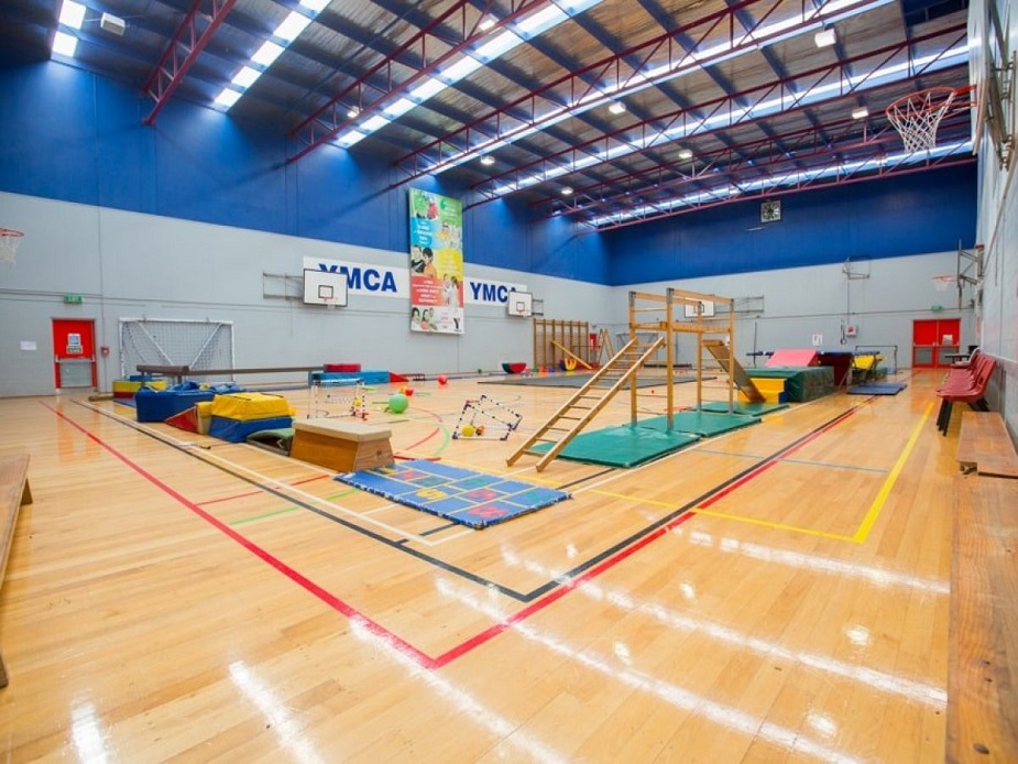 Sports hall with timber floor, YMCA branding and gymnastics equipment
