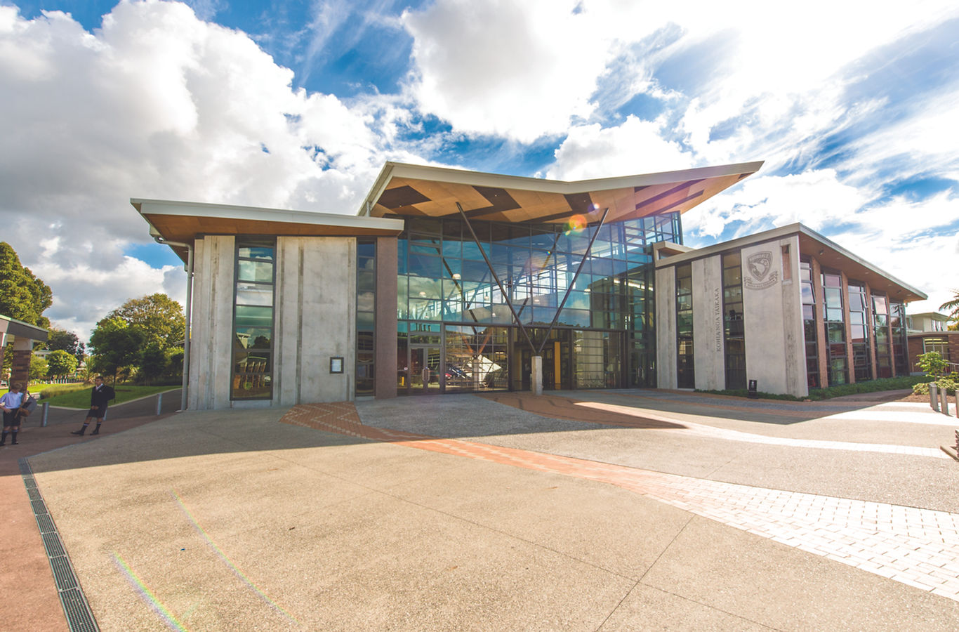 Contemporary building with concrete columns, large glazed facade, and timber canopy entrance