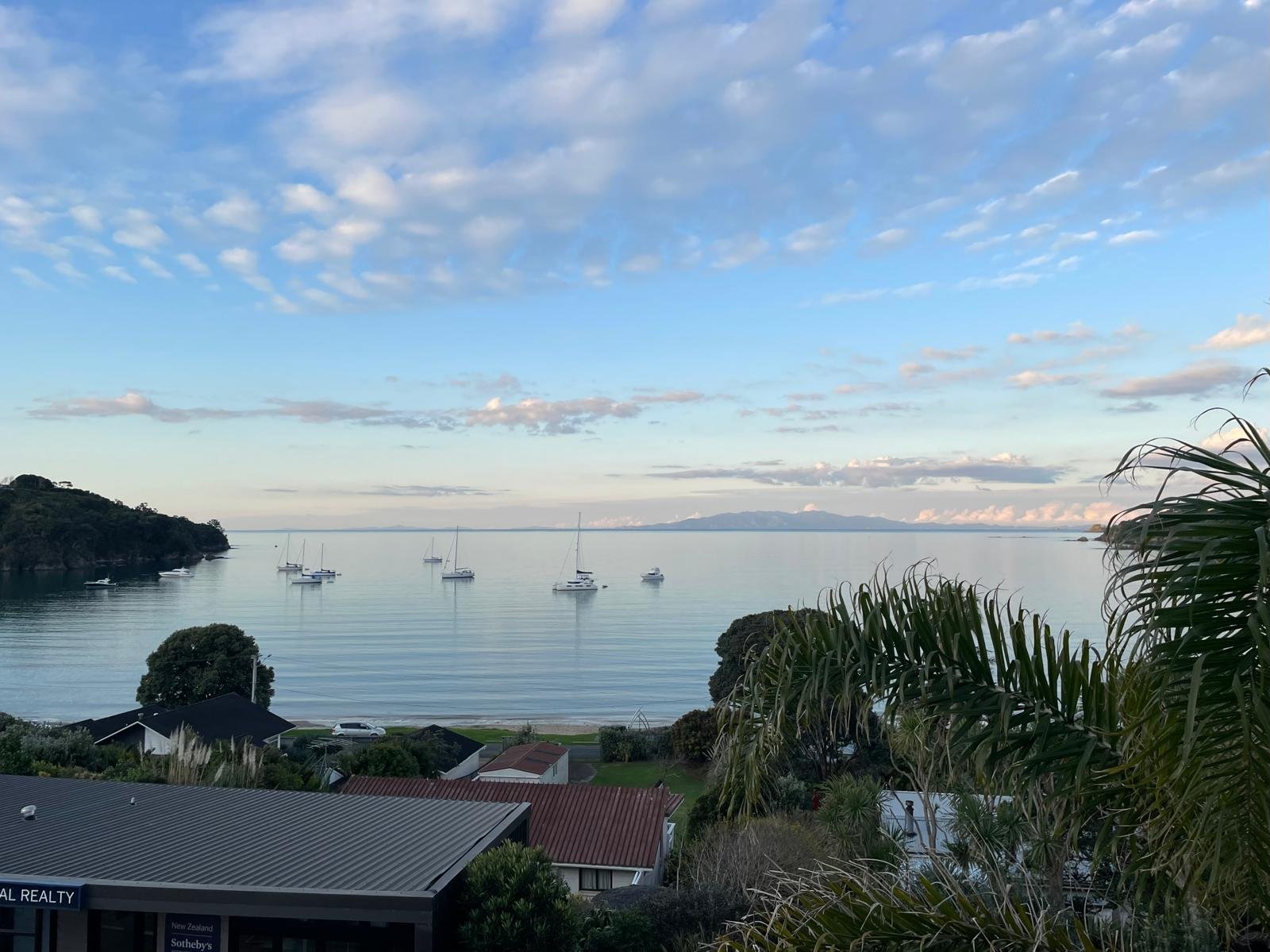 Coastal view with moored sailboats on calm water at dusk