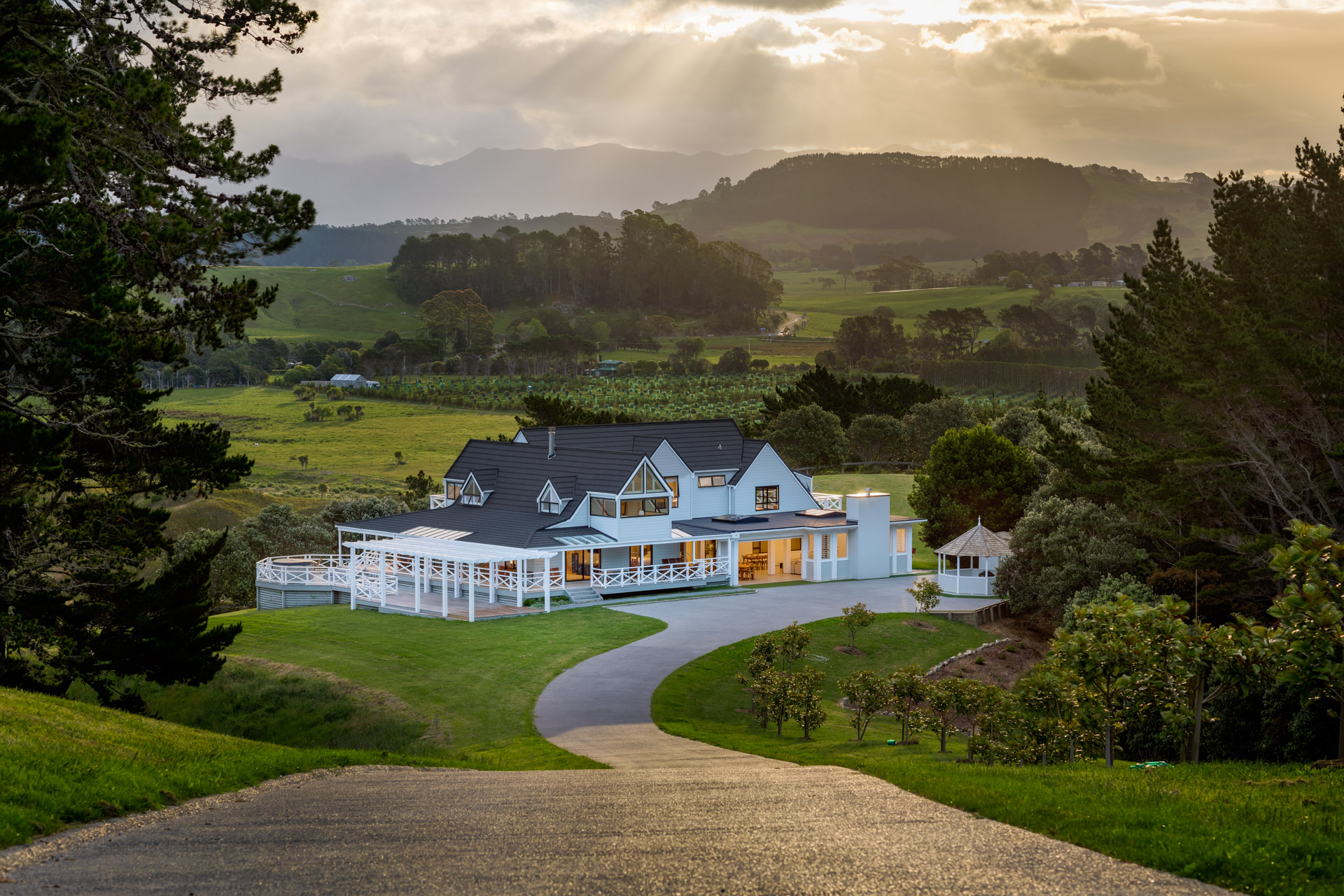 Main building lit at dusk seen from the hilltop driveway with valley and hills behind
