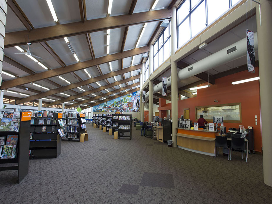 Library interior with high timber-beamed ceiling, book displays, and service counter