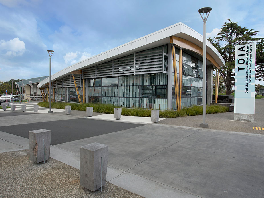 Contemporary low-rise building with angled roof, timber columns, louvre cladding and signage