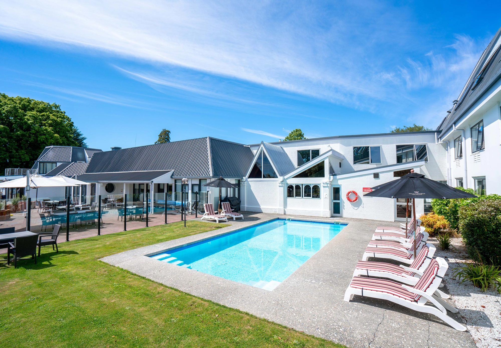 Outdoor swimming pool with sun loungers and white hotel buildings