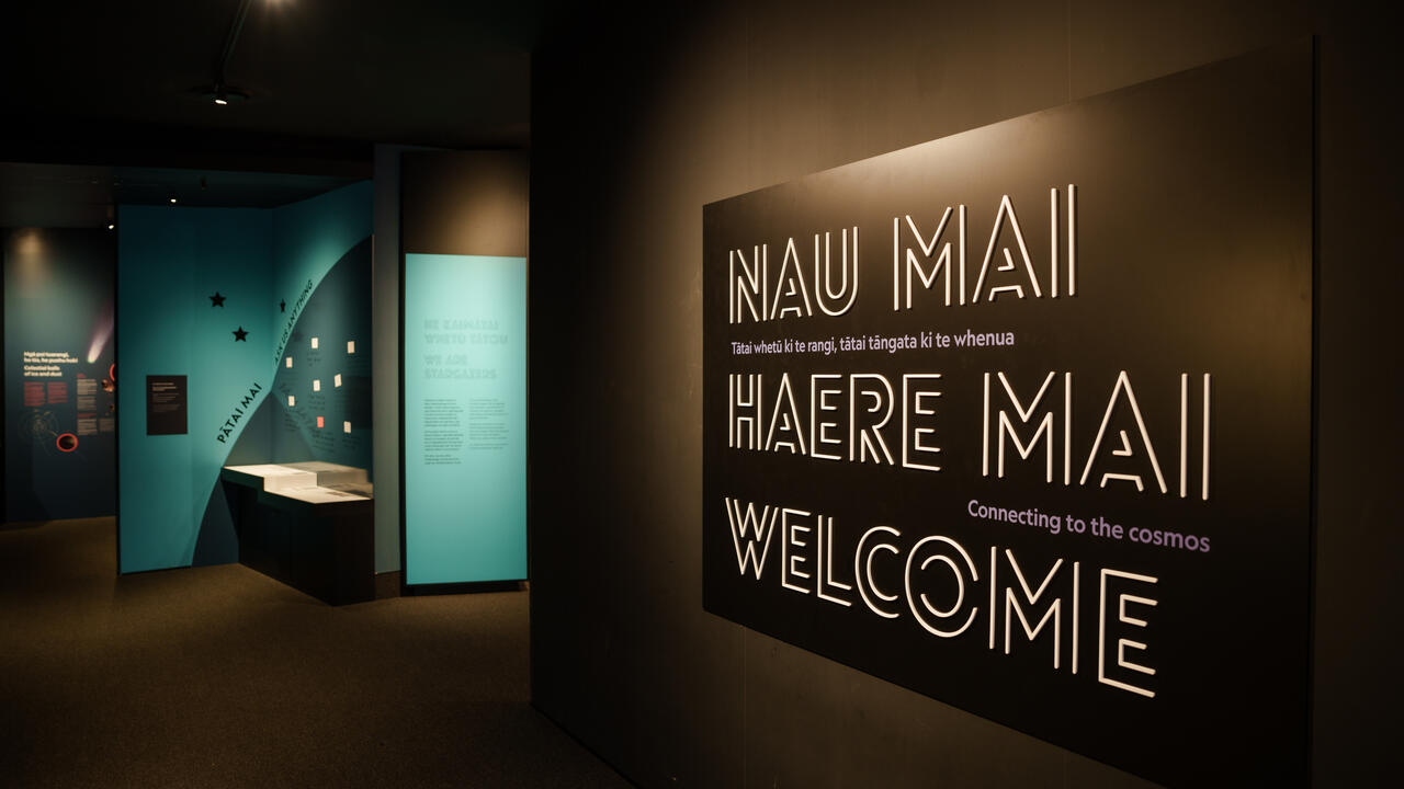 Dark museum entrance corridor with welcome signage and exhibition panels