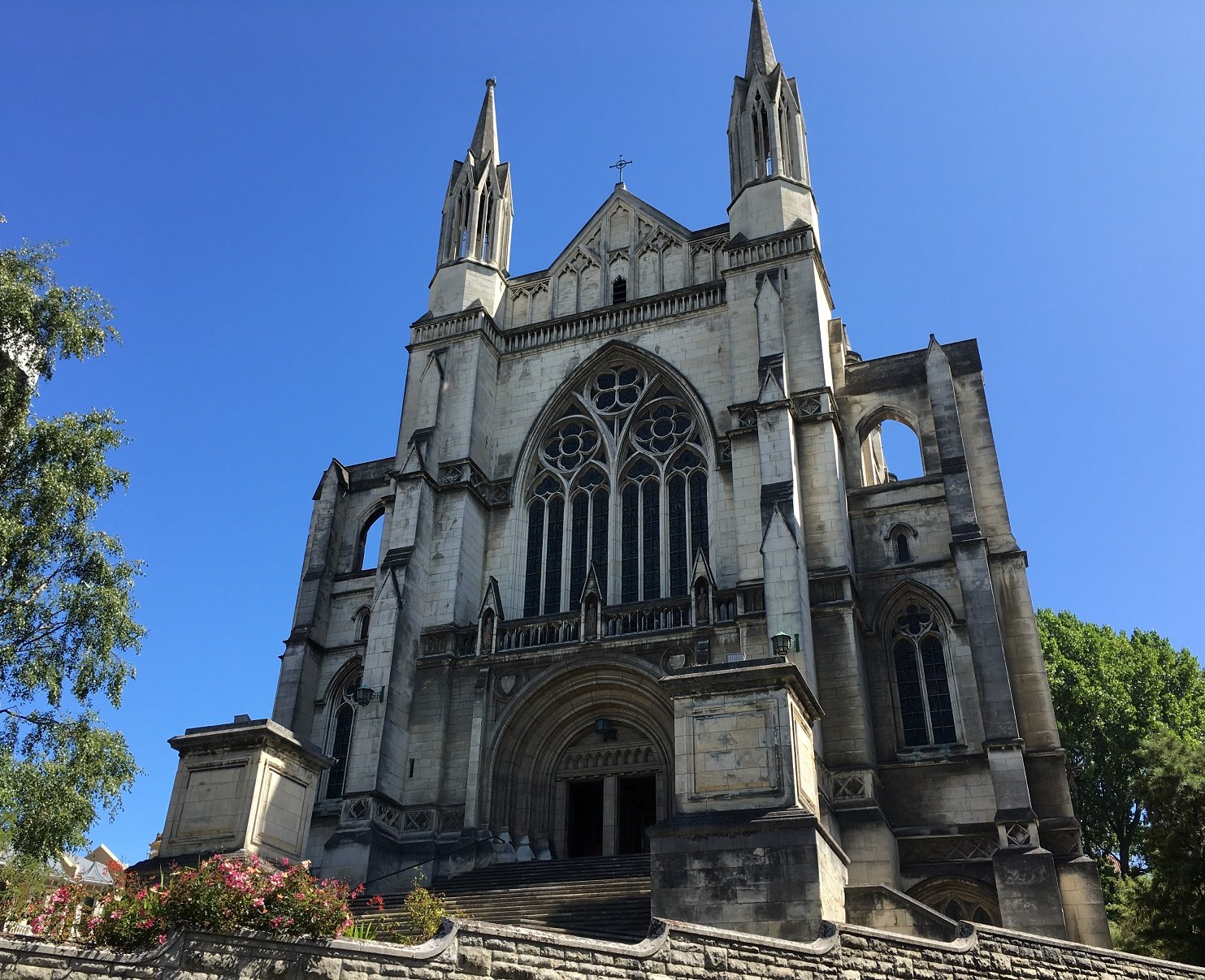 Large Gothic stone cathedral exterior with twin spires, rose window, grand entrance steps