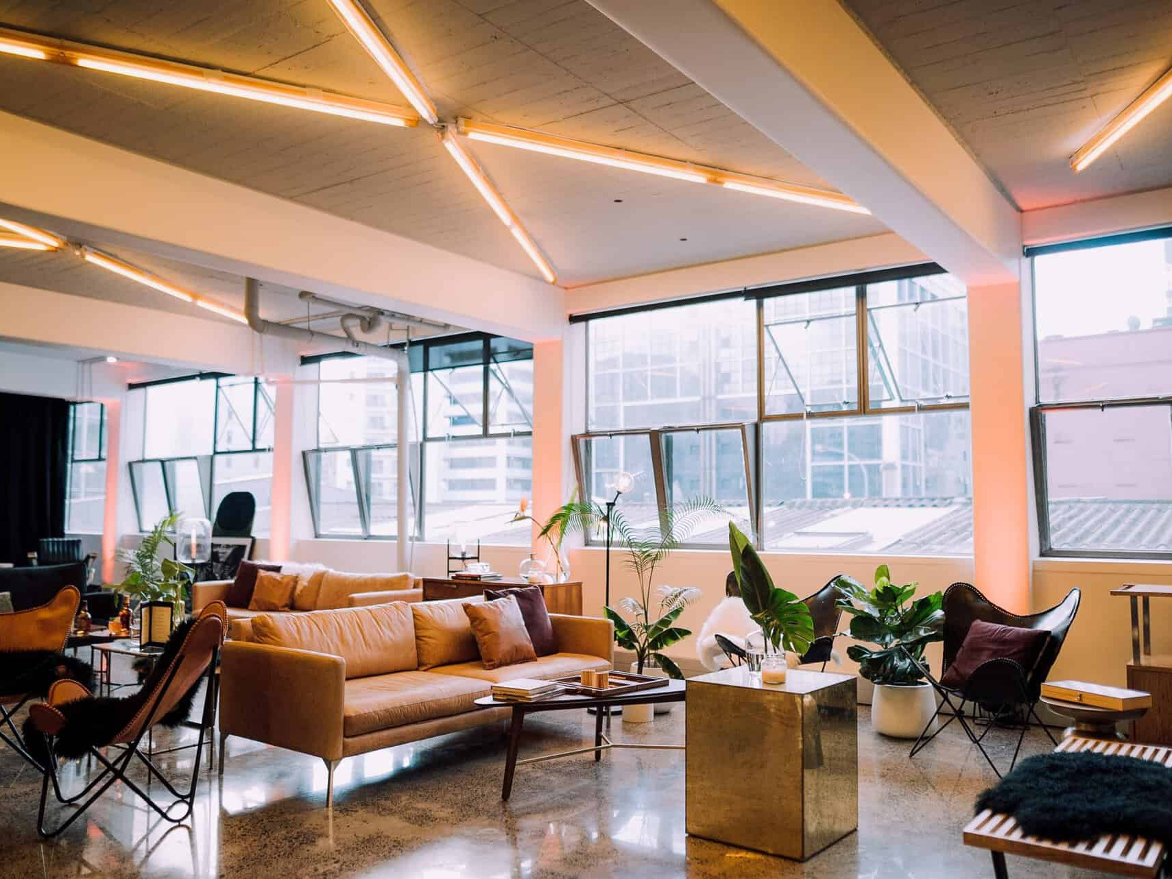 Bright industrial lounge space with leather sofas and neon ceiling strips