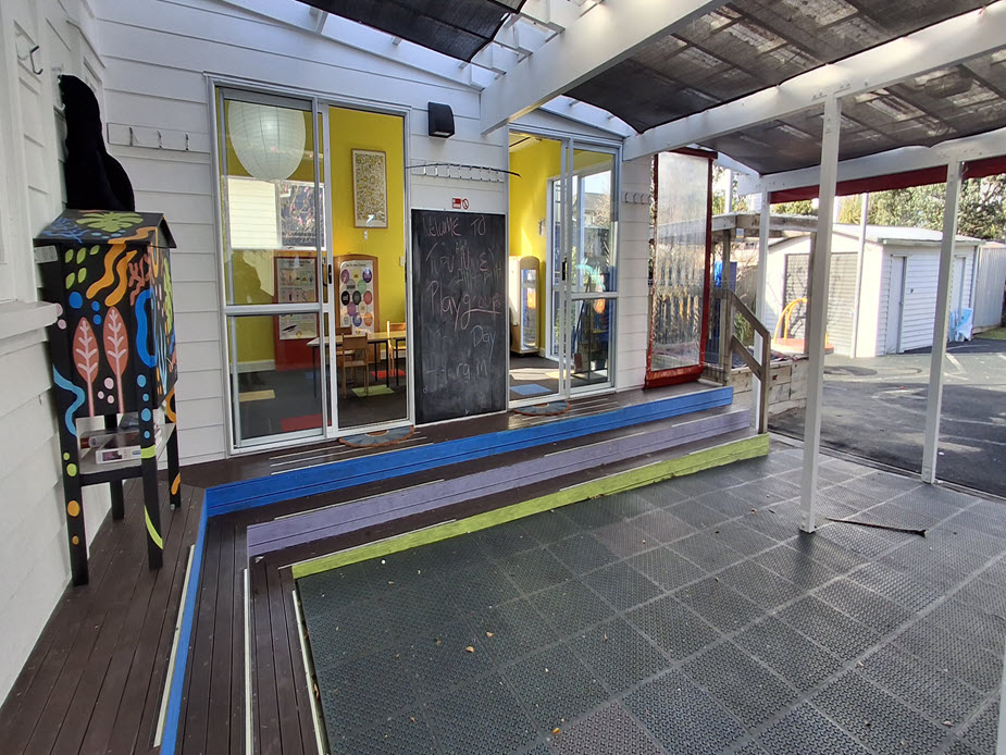 Covered deck area outside colourful playgroup room with ramp and shade cloth