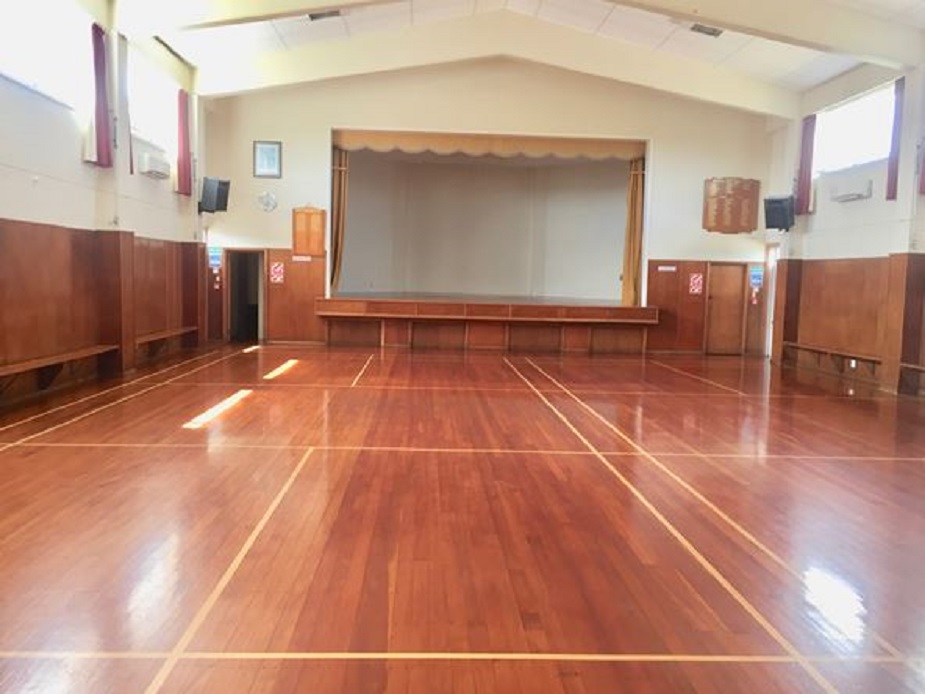 Large hall with polished timber floor and raised platform at one end