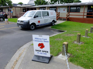 Community house building with van parked outside and A-frame sign on footpath