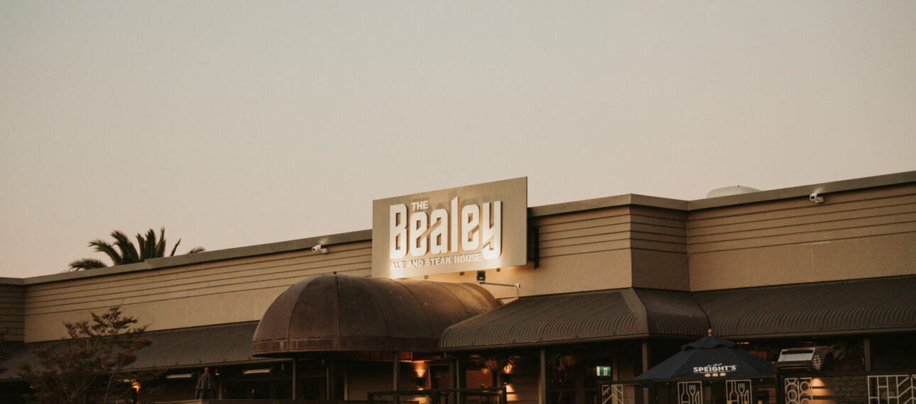 The Bealey signage lit up on a low-rise commercial building at dusk
