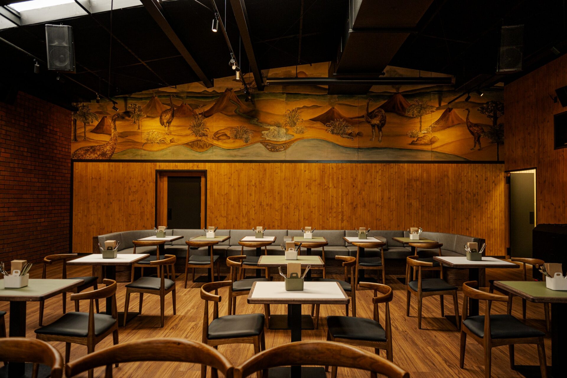 Timber-panelled dining room with painted landscape mural, booth seating and round tables
