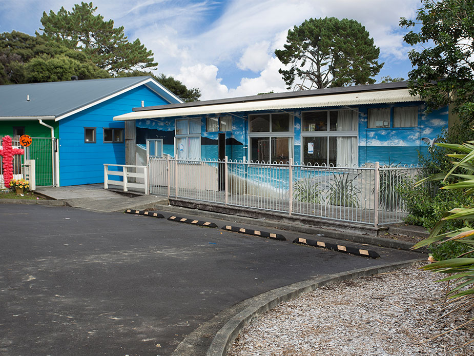 Single-storey blue-painted community hall exterior with fenced entrance