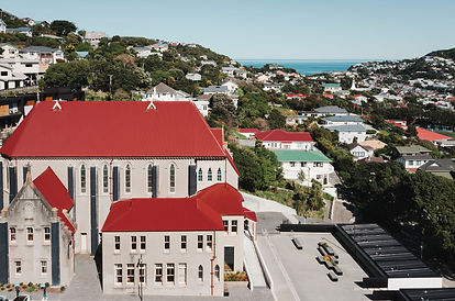 Aerial view of Gothic stone chapel with red roof in a Wellington suburb near the coast