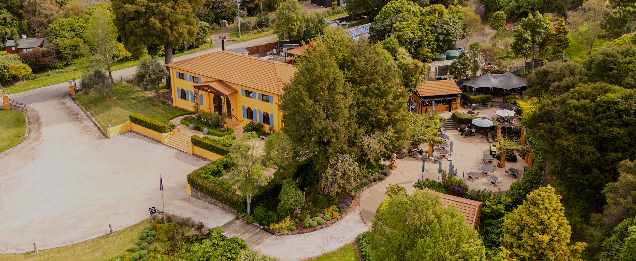 Aerial view of ochre Mediterranean-style winery building amid trees and lawns
