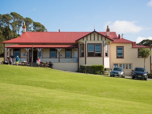 Heritage lodge building with red roof and verandah on a grassed site