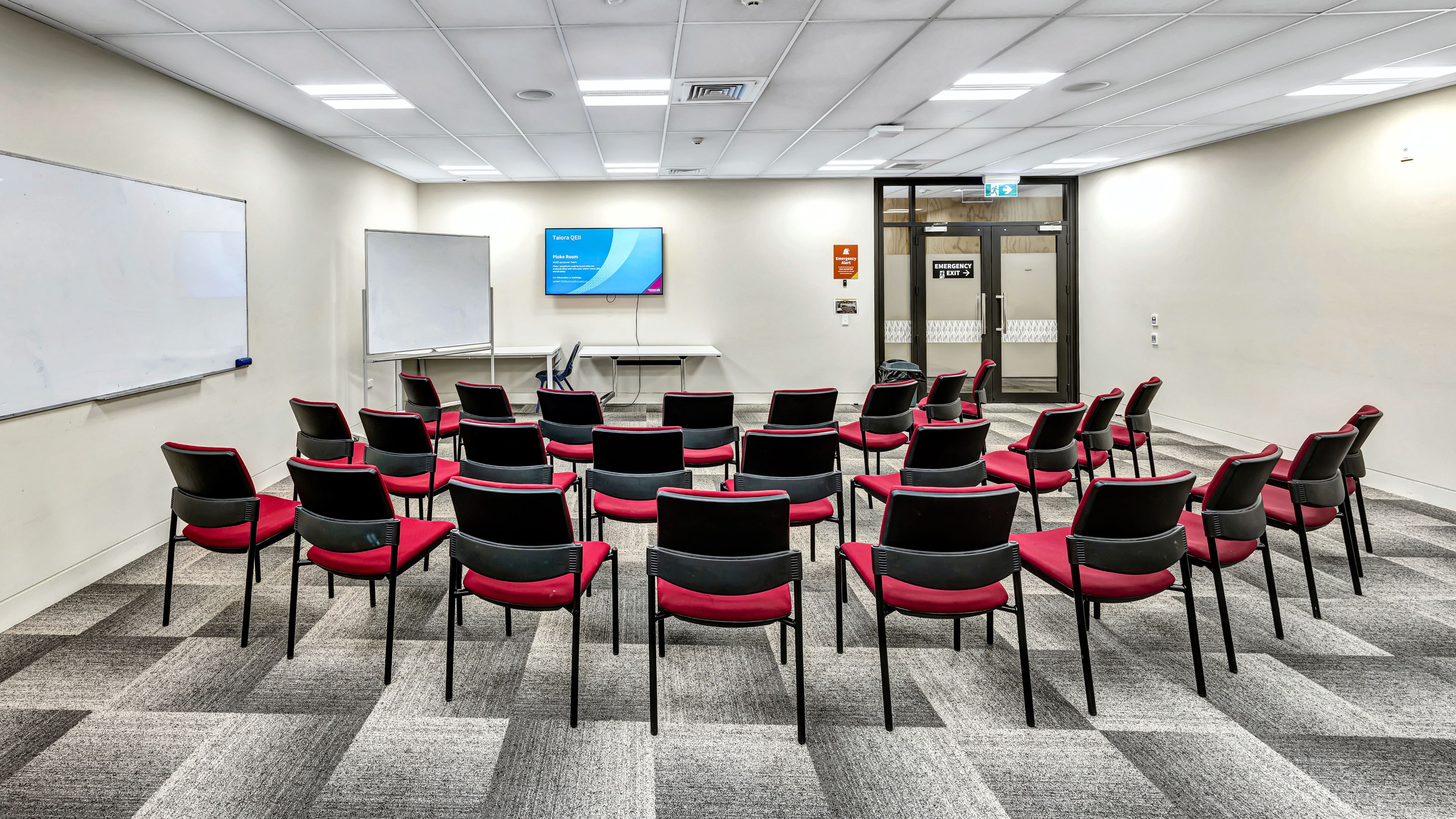 Meeting room with chairs arranged in a horseshoe, whiteboard, and projection screen