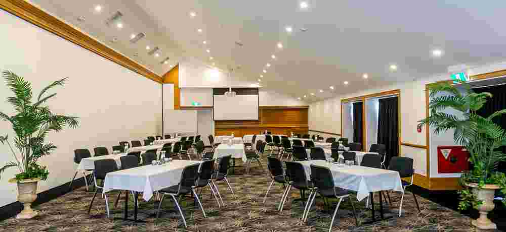 Conference room with clustered round tables, projection screen and gold chandeliers