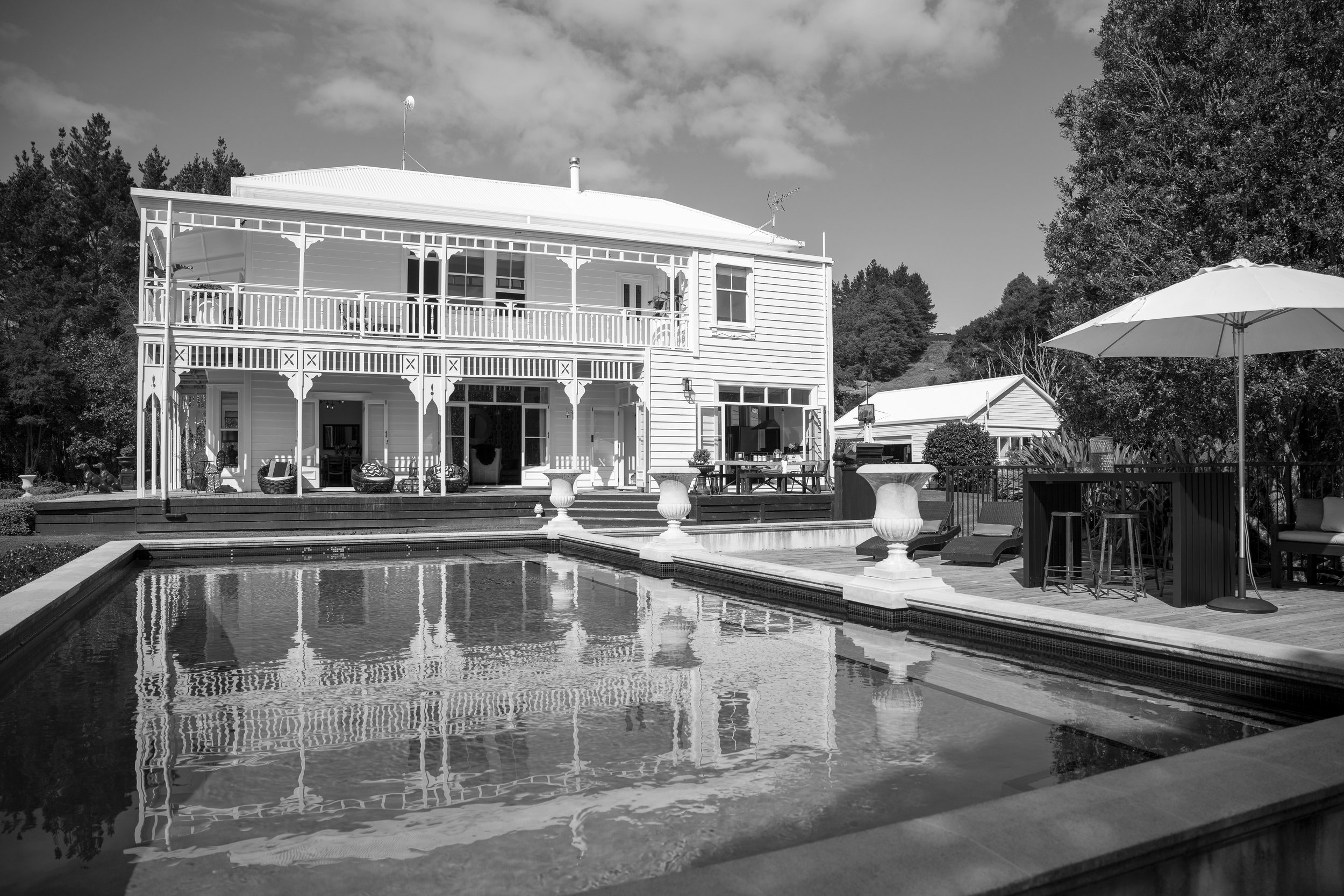 Two-storey white weatherboard villa with wraparound verandahs, a pool terrace and outdoor bar