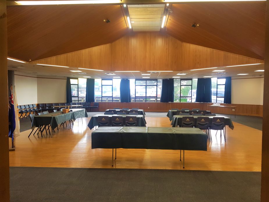 Large hall with vaulted timber ceiling, tables set with dark cloths and chairs